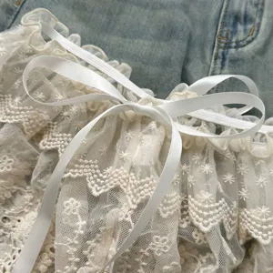 Detailopname van witte kanten rokverlenging met satijnen strik, fijne mesh stof textuur.