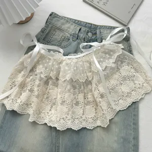 Gedetailleerd overzicht van een witte kanten gelaagde rok over denim shorts.