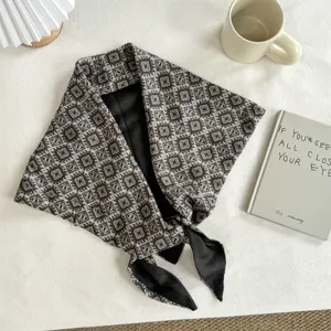 Close-up detail of retro ethnic botanical patterned triangle scarf with black lining and tied knot.