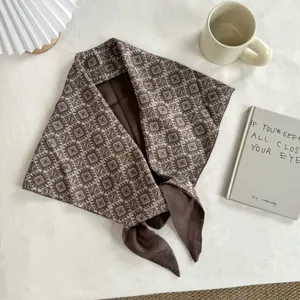 Detailed shot of retro ethnic botanical patterned brown triangular scarf, soft fabric texture.