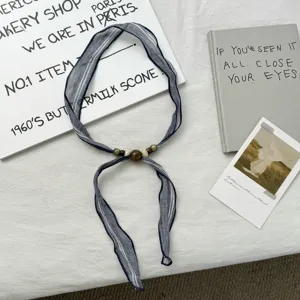 Detailed view of vintage striped ribbon scarf with bead decor, ideal for summer styling.