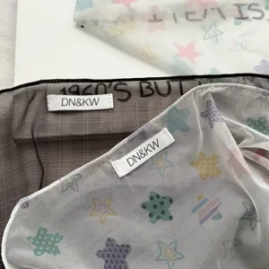 Primo piano dettagliato di sciarpa in rete trasparente con stampa di stelle ed etichetta.