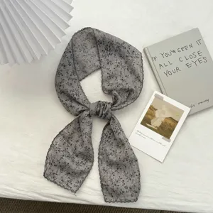 Detailaufnahme eines grauen Schals mit Blumenmuster, retro Ästhetik, vielseitiges Accessoire.