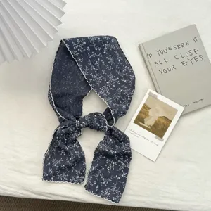 Detailaufnahme eines vintage dunkelblauen schmalen Schals mit Blumenmuster und Bogenkante.