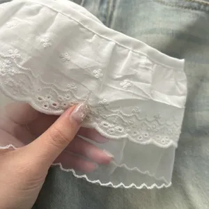 Detailopname van de witte kanten mesh rokverlenger met fijn borduursel en mooie stofstructuur.