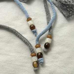 Primer plano de cordones tejidos con cuentas ámbar y blancas elegantes y finas.