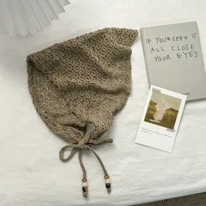 Pañuelo triangular de punto calado caqui con tiras y abalorios, accesorio de moda elegante.