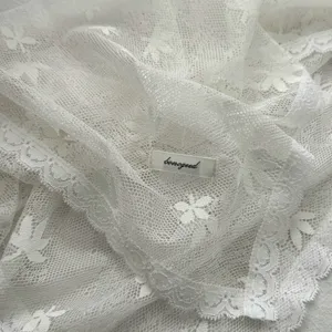 Detailopname van de witte kanten sjaal met een fijn en elegant bloemenpatroon.