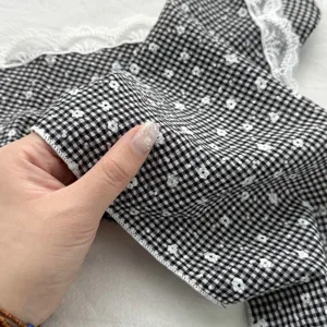 Close-up detail of black and white checkered fabric with small floral print and white lace trim.