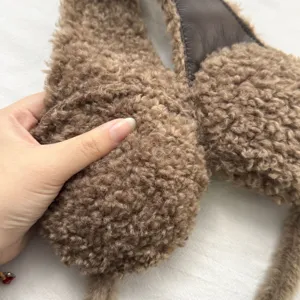 Detalle de orejeras de invierno de lana de cordero con textura de felpa suave y cálida.
