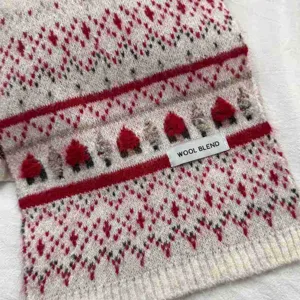 Primo piano dettagliato di accogliente sciarpa invernale in maglia rossa e bianca con motivo natalizio.