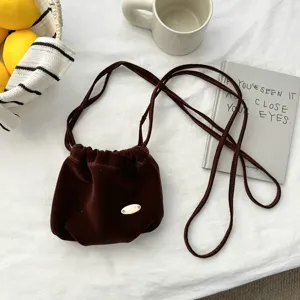 Close-up of a vintage brown velvet drawstring pouch bag, elegant shoulder strap detail.