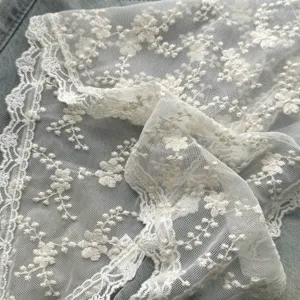 Detail van witte kanten driehoekige sjaal, fijn bloemenborduurwerk, mesh-stof, vintage stijl.