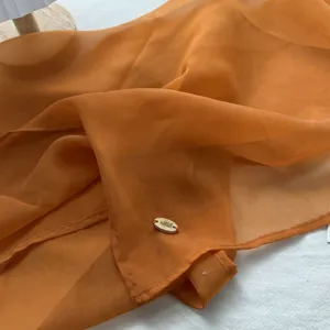 Oranje transparante sjaal detail close up lichtgewicht modieuze doek lente accessoire
