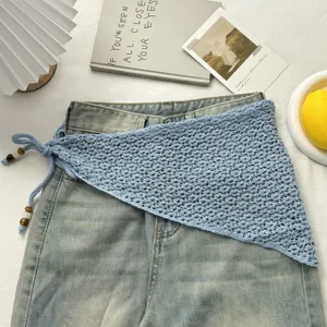 Detalle de pañuelo triangular calado de punto azul con bonitos lazos de cuentas y perlas.