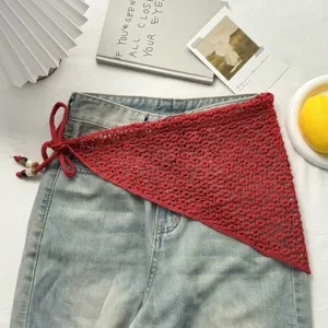 Vista detallada del pañuelo triangular de punto rojo y falda sobre jeans con cuentas.