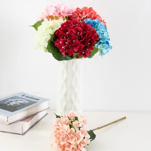 Vue détaillée d'un bouquet d'hortensias artificiels en soie colorée avec vase blanc pour déco.