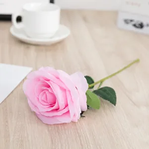 Vista dettagliata di una singola rosa artificiale in seta rosa con foglie per arredare.
