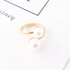Gros plan détail d'un anneau ouvert doré avec deux perles blanches, élégante boucle d'écharpe.