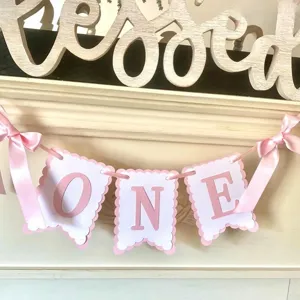 Detailed shot of pink and white ONE letter banner with cute ribbon bows for baby birthday decor.