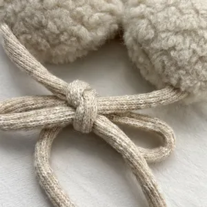 Detailansicht von Winter Plüsch Ohrenschützern mit Strickkordel, kuschelig warmes Fleece Material.