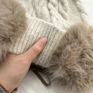 Nahaufnahme der beigen Strick-Wintermütze mit Plüschohrschützern und dicker Textur.