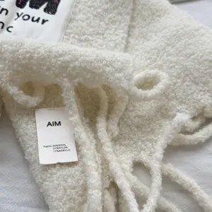 Detailed view of white fluffy wool blend scarf texture and tag showing material composition.