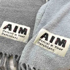 Detailed close-up of soft knitted wool winter scarf with fringe and brand label design.