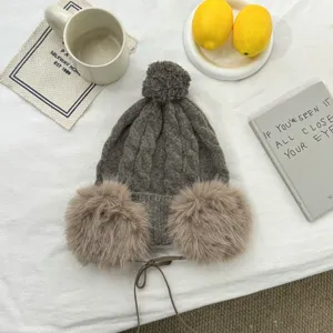 Detailansicht der kuscheligen Winter-Strickmütze mit Ohrenklappen und flauschigem Bommel.