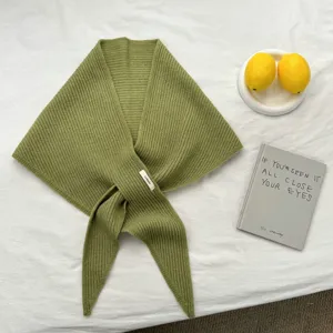 Detalle de bufanda triangular de punto verde, accesorio de moda de invierno acogedor.