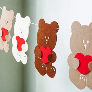 Détail bannière cœur feutre ours, idéal pour fête d'anniversaire enfants et décoration murale.