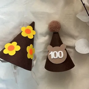 Felt birthday hat detail showing cute brown party caps with yellow flowers and bear decor.