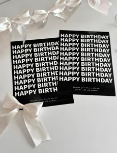 Detailed close-up of black birthday cards with white typography and elegant white ribbons.