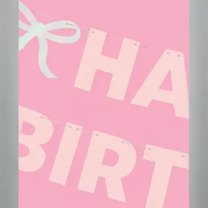 Glitter birthday paper banner detail, shiny letter bunting and bow decor for party setup.