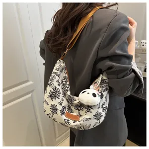 Detailed shot of casual canvas shoulder bag with black print and cute panda pendant.