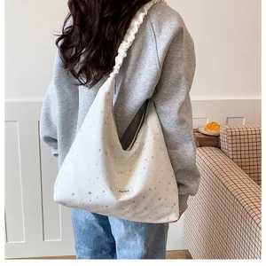 Detail view of a white slouchy hobo shoulder bag featuring allover silver star prints and gathered strap.