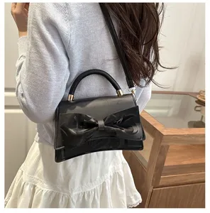 Detail view of the black minimalist women handbag featuring a large stylish bow and strap.