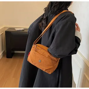 Detailed view of the lightweight nylon crossbody shoulder bag, highlighting front zip pocket.
