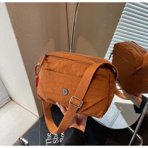 Minimalist brown nylon crossbody bag featuring wide strap and stylish metallic M logo.