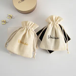 Close-up details of beige linen cotton drawstring jewelry storage pouches with custom printed logo.