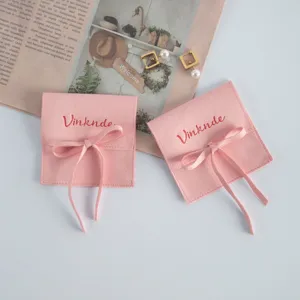 Sacchetto portagioie in camoscio rosa con fiocco, ideale per custodire anelli e collane in sicurezza.