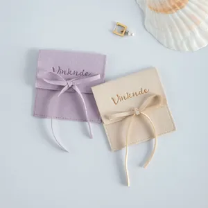 Nahaufnahme weicher Samtschmuckbeutel mit Schleifenbändern in Lila und Beige, Detailansicht.