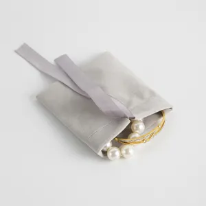 Grauer Samt Schmuckbeutel mit Schleife und Perlenarmband Detailansicht für Geschenkverpackung