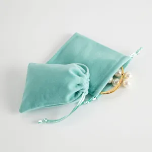 Fluwelen sieradenzakje met trekkoord en parelarmband detail voor geschenkverpacking en opslag.