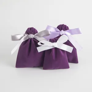 Detail of purple velvet jewelry pouch bags with delicate satin ribbon bows, elegant gift packaging.