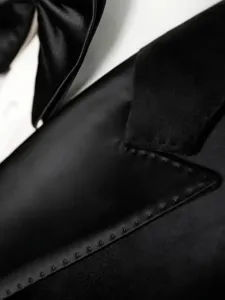 Detalle de la solapa de la chaqueta de traje negra elegante para hombre con textura fina.