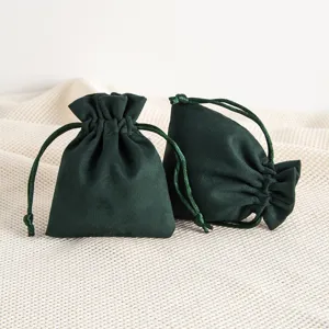 Detail view of dark green velvet drawstring jewelry pouch, soft gift storage bag for small items.