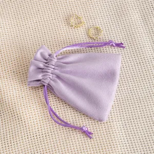 Purple velvet jewelry pouch detail showing soft texture and gold pearl hoop earrings display.