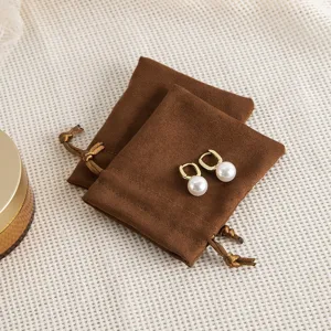 Nahaufnahme von braunen Wildleder Schmuck Beuteln mit Kordelzug und Perlen Ohrringen.