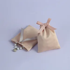 Detailaufnahme von Wildleder-Schmucktaschen mit Schleifen und Perlenarmband-Zubehör.
